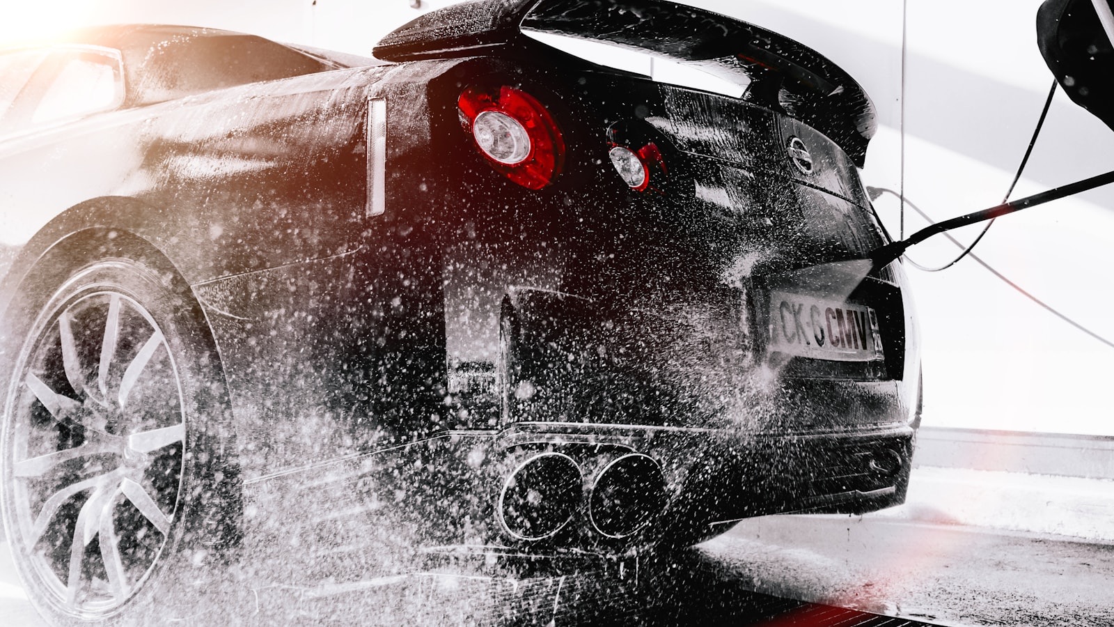 Black sports car getting a high-pressure rinse in the tunnel