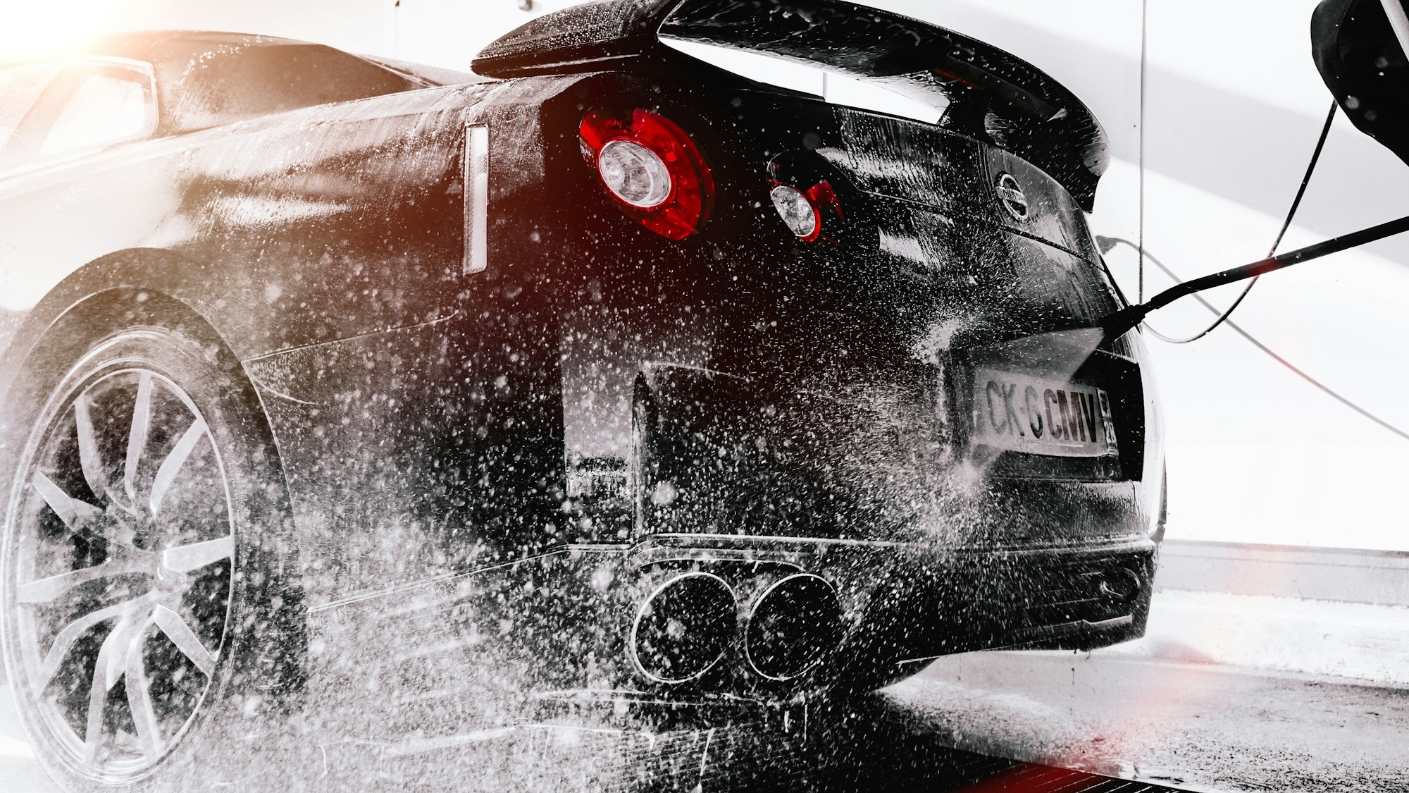 Car being washed with water spray at Washentire Auto Wash